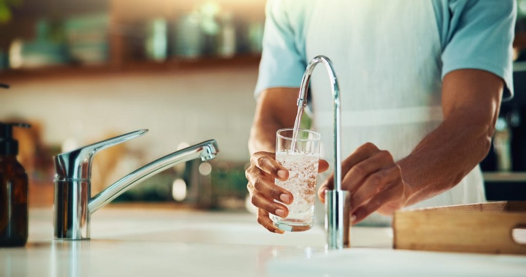 Stock image of a glass being filled with tap water from a sink.