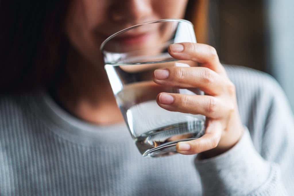 Stock image of a woman drinking water from a glass.