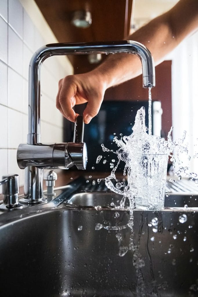 Stock image of a glass being filled with tap water.