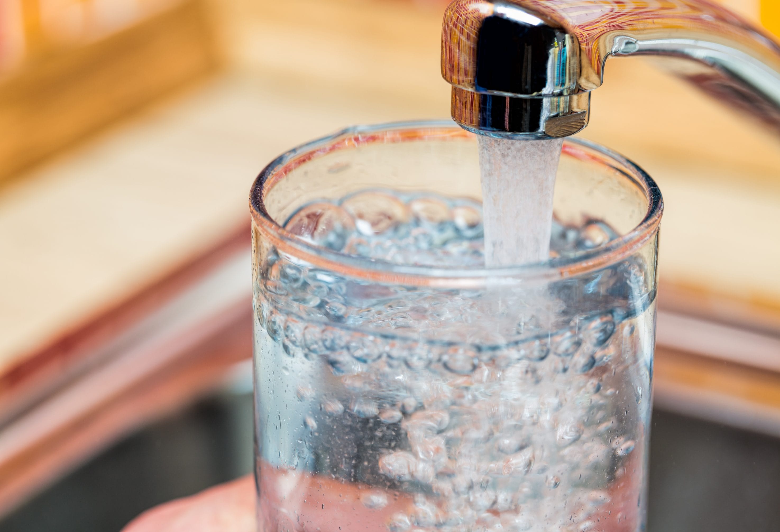 Stock image of water pouring from a faucet into a glass.